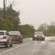 A car is driven past a flooded road at Passage West, Co Cork (Noel Sweeney/PA)